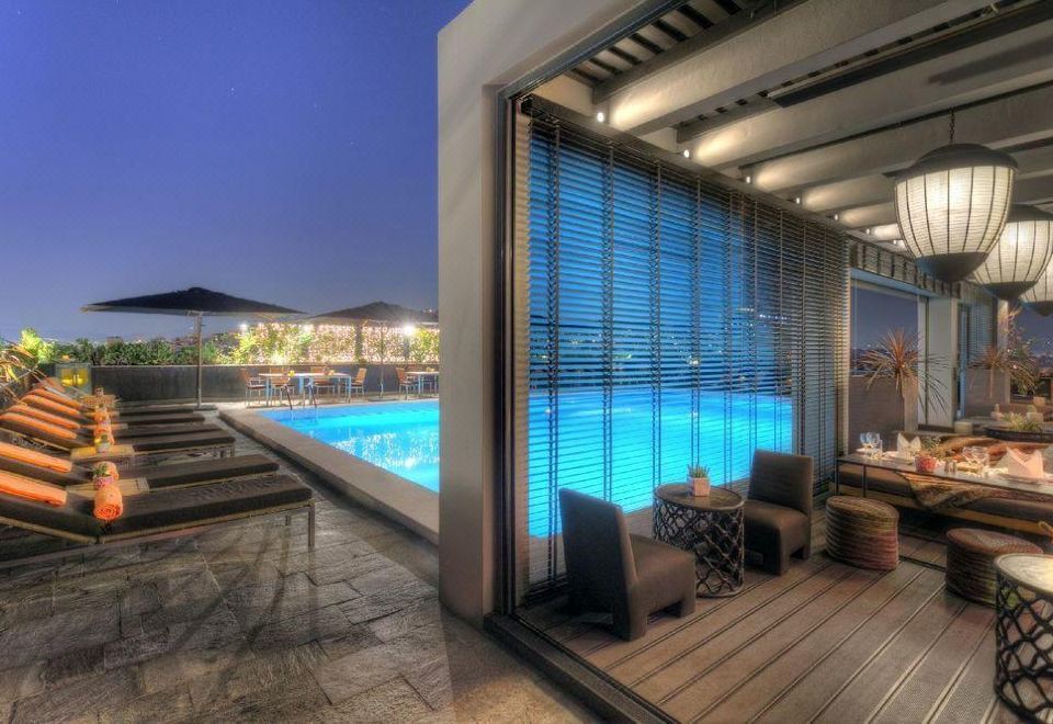 a modern building with a large window and sliding glass door leading to an outdoor swimming pool , surrounded by comfortable seating at President Hotel