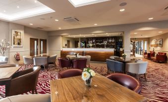 a modern restaurant with wooden tables , chairs , and a bar , decorated with red and white checkered floor patterns at Ramsey Park Hotel