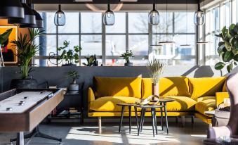 a modern living room with yellow couches , a foosball table , and large windows overlooking the city at Pier 5 Hotel