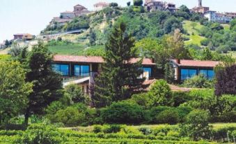 a house with a red roof is perched on a hillside overlooking a vineyard and a castle at Arborina Relais