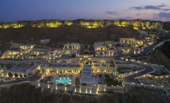 a nighttime aerial view of a small town with a pool in the center , surrounded by mountains at Kayakapi Premium Caves Cappadocia
