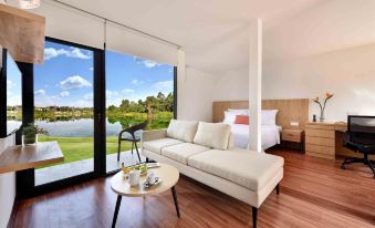 a modern living room with large windows offering a view of a golf course , featuring a white couch and coffee table at Lakeview Terrace Resort Pengerang