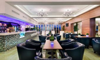a modern , well - lit restaurant with blue walls and white ceiling , featuring black leather chairs and wooden tables arranged around a central bar area at Swan River Hotel