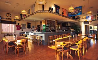 a restaurant with wooden tables and chairs , a bar area , and a large wall of beer advertisements at Shilo Inn Suites Klamath Falls