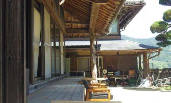 a traditional japanese building with wooden beams and large windows , surrounded by greenery and a stone path at Saraya