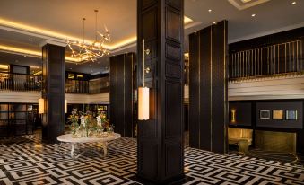 a luxurious hotel lobby with black and white checkered floor , gold accents , and a large chandelier at Hilton Vienna Plaza