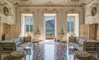 a large , ornate room with a marble floor and high ceilings is adorned with potted plants and benches at Grand Hotel Tremezzo