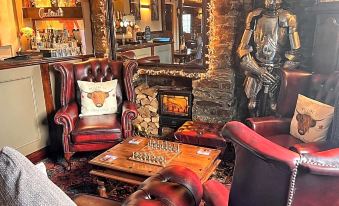 a cozy living room with a fireplace and red leather chairs , creating a warm and inviting atmosphere at The Mary Tavy Inn