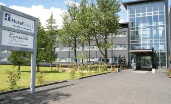 a modern building with trees and a path leading to the entrance , under a clear blue sky at Hotel Selfoss