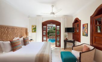 a luxurious hotel room with a king - sized bed , a couch , and a balcony overlooking a swimming pool at Cap Maison Resort & Spa