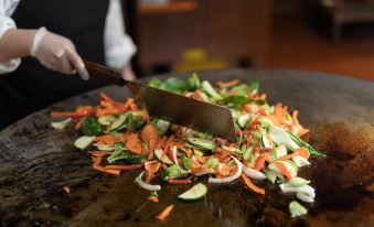 a person is cutting up a variety of vegetables on a table , with a knife in the process at Lodge at Feather Falls Casino