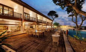 a large wooden deck with tables and chairs overlooks a body of water at night at The Fortress Resort & Spa