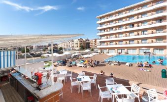 a large hotel with a pool and outdoor seating area , including chairs and tables , under a clear blue sky at Hotel Sorra Daurada Splash