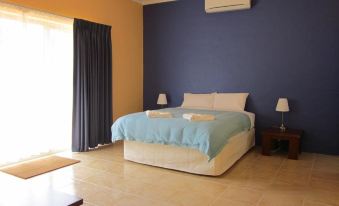 a large bed with a blue blanket is in the middle of a room with blue walls and a window at Chalets on Stoneville