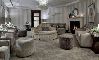 a luxurious living room with a large couch , several chairs , and a fireplace , decorated with white walls and gray carpet at The Del Monte Lodge Renaissance Rochester Hotel & Spa