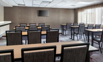 a conference room with rows of chairs and tables , a television mounted on the wall , and a window at Courtyard Newburgh Stewart Airport