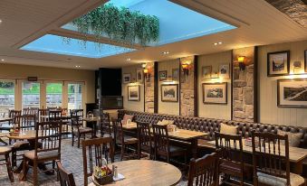 a large dining room with multiple tables and chairs , as well as a skylight above at The Bridge Inn