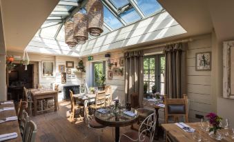 a cozy living room with wooden furniture , including chairs , a dining table , and a fireplace at The Frogmill Hotel