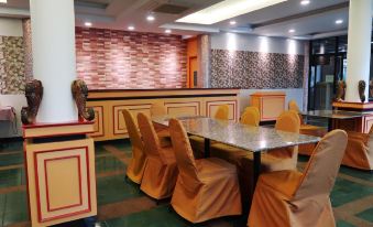 a dining room with a long table surrounded by chairs , and a brick wall in the background at Triple Resort