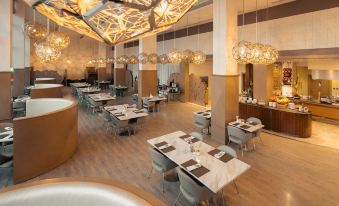 a large dining area with multiple tables and chairs , as well as a buffet table filled with various food items at Radisson Blu Hotel Buraidah