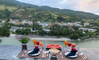 a table set with plates , wine glasses , and fruit is set up on a balcony overlooking a river at Hotel River Valley
