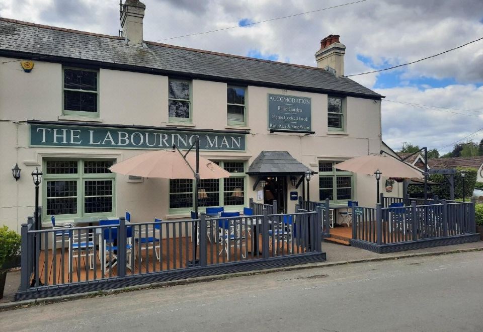 a brick building with a restaurant called the labouring man , which is surrounded by blue chairs and umbrellas at The Labouring Man