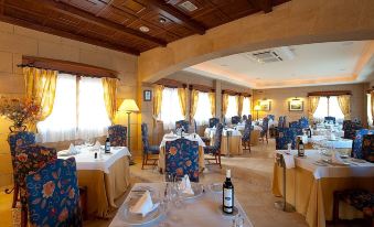 a large dining room with multiple tables and chairs arranged for a group of people to enjoy a meal together at Elba Castillo San Jorge & Antigua Suite Hotel