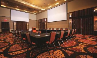 a conference room with a long table , chairs , and multiple screens set up for a meeting at Osage Casino Hotel