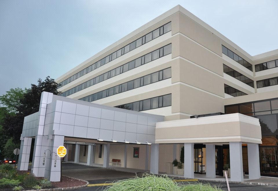 a large white building with a yellow sign on the side and a parking lot in front at Holiday Inn Clinton - Bridgewater