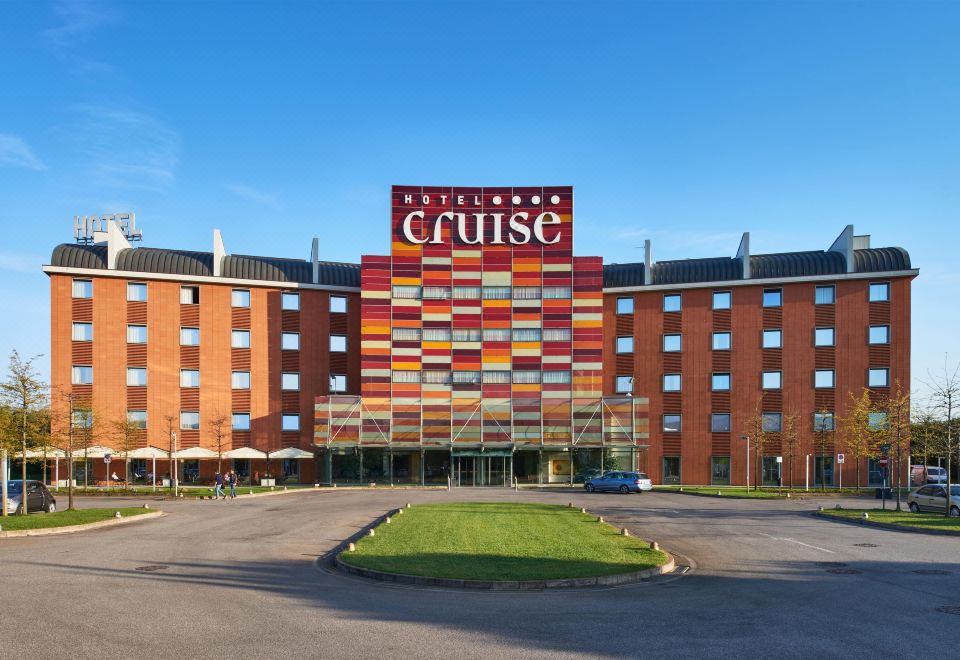 "a large hotel building with a sign that reads "" cuisc "" in front of it , surrounded by grass" at Hotel Cruise