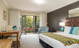 a hotel room with a bed , chair , and sliding glass door leading to a balcony at Berry Village Boutique Motel