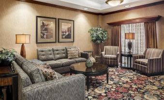 a well - decorated living room with a gray couch , wooden coffee table , and framed pictures on the wall at Ameristar Casino Hotel Council Bluffs