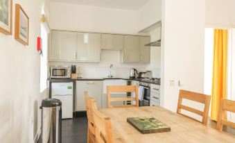a small , well - equipped kitchen with a dining table and chairs , as well as a stove and refrigerator at Kennels