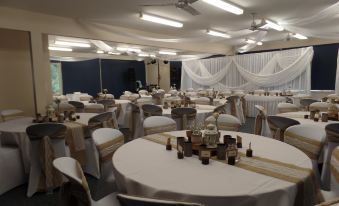 a large banquet hall with white tablecloths and gold accents is set up for a wedding reception at Waterfront Retreat at Wattle Point