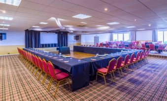 a large conference room with multiple tables and chairs , a blue tablecloth on the table , and a window in the background at Springfield Hotel and Restaurant