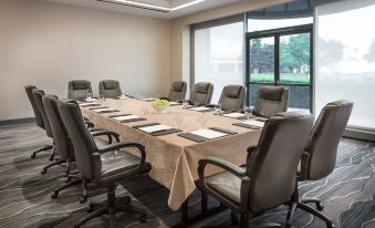 a large conference room with a long table , multiple chairs , and a view of a building outside the window at Hyatt Regency San Francisco Airport