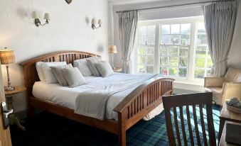 a bedroom with a large bed , wooden headboard , and two lamps on either side of the bed at The Brown Horse Inn