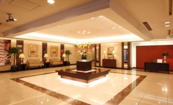 a spacious lobby with a large vase of flowers in the center and chairs arranged around it at Hotel Hokke Club Hiroshima