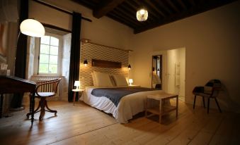 a spacious bedroom with hardwood floors , a large bed , and a wooden table near the window at Chateau Saint Martin B&B