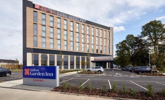 a large building with the hilton garden inn sign in front of it , surrounded by trees at Hilton Garden Inn Doncaster Racecourse