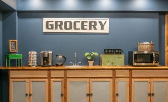"a counter with various appliances and drinks , including a coffee maker , in front of a blue wall with a sign that says "" grocery ""." at Mad River Lodge