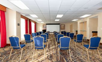 a conference room with rows of chairs arranged in a semicircle , and a projector screen mounted on the wall at Hampton Inn & Suites Pittsburg