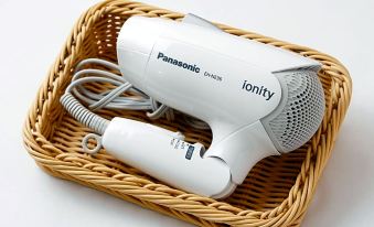 a white panasonic hair dryer is placed in a wicker basket , ready for use at Hotel Resol Machida