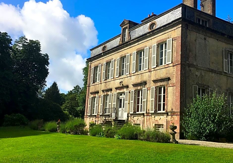 a large stone building with a red roof and white windows is surrounded by green grass and trees at Chateau de Beaulieu