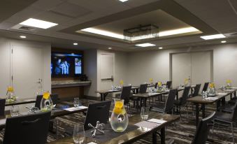 a conference room with multiple tables , chairs , and a tv displaying a tv screen on the wall at Renaissance Allentown Hotel