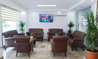 a room with brown leather chairs arranged in a sitting area , along with a television mounted on the wall at Palm Beach Hotel