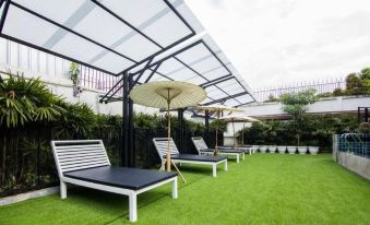 a backyard with several lounge chairs and umbrellas , providing a relaxing environment for guests at Blue Lagoon Hotel