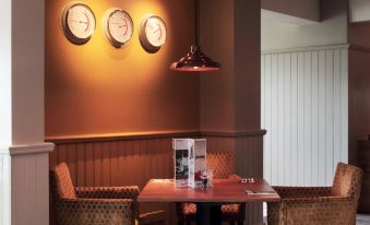 a dining room with a table and chairs , surrounded by three wall clocks on the wall at Darlington East (Morton Park)