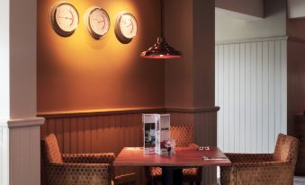 a dining room with a wooden table , chairs , and three clocks hanging on the wall at Darlington East (Morton Park)