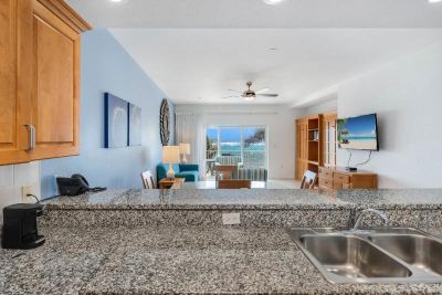 a kitchen with a granite countertop , sink , and television in a living room area with blue walls at Wyndham Reef Resort Grand Cayman